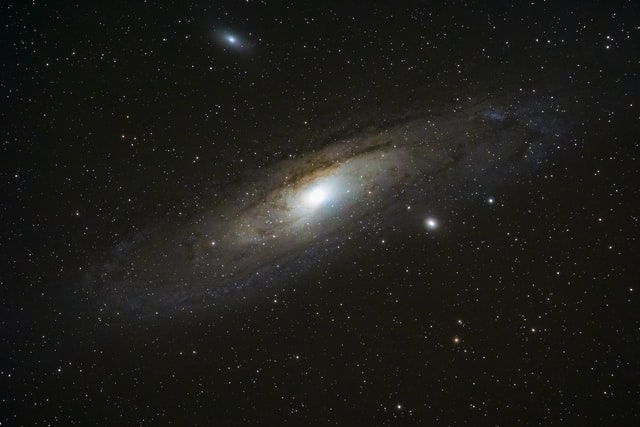 The Andromeda Galaxy like a swirling smoke, surrounded by stars that look like tiny dots