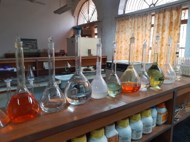 Ten volumetric flasks containing different types of transparent and colored liquid