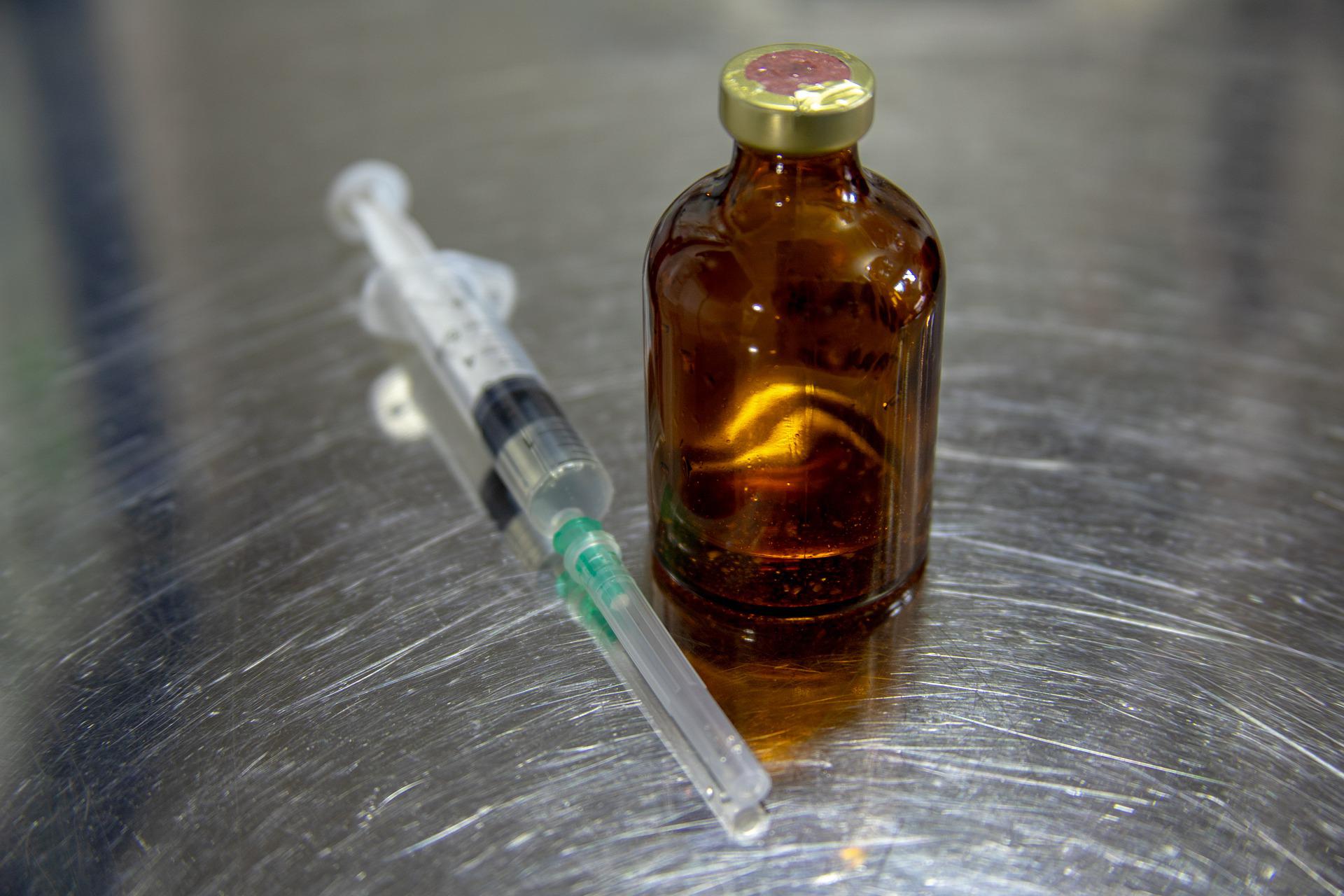 A syringe sitting beside a closed brown bottle