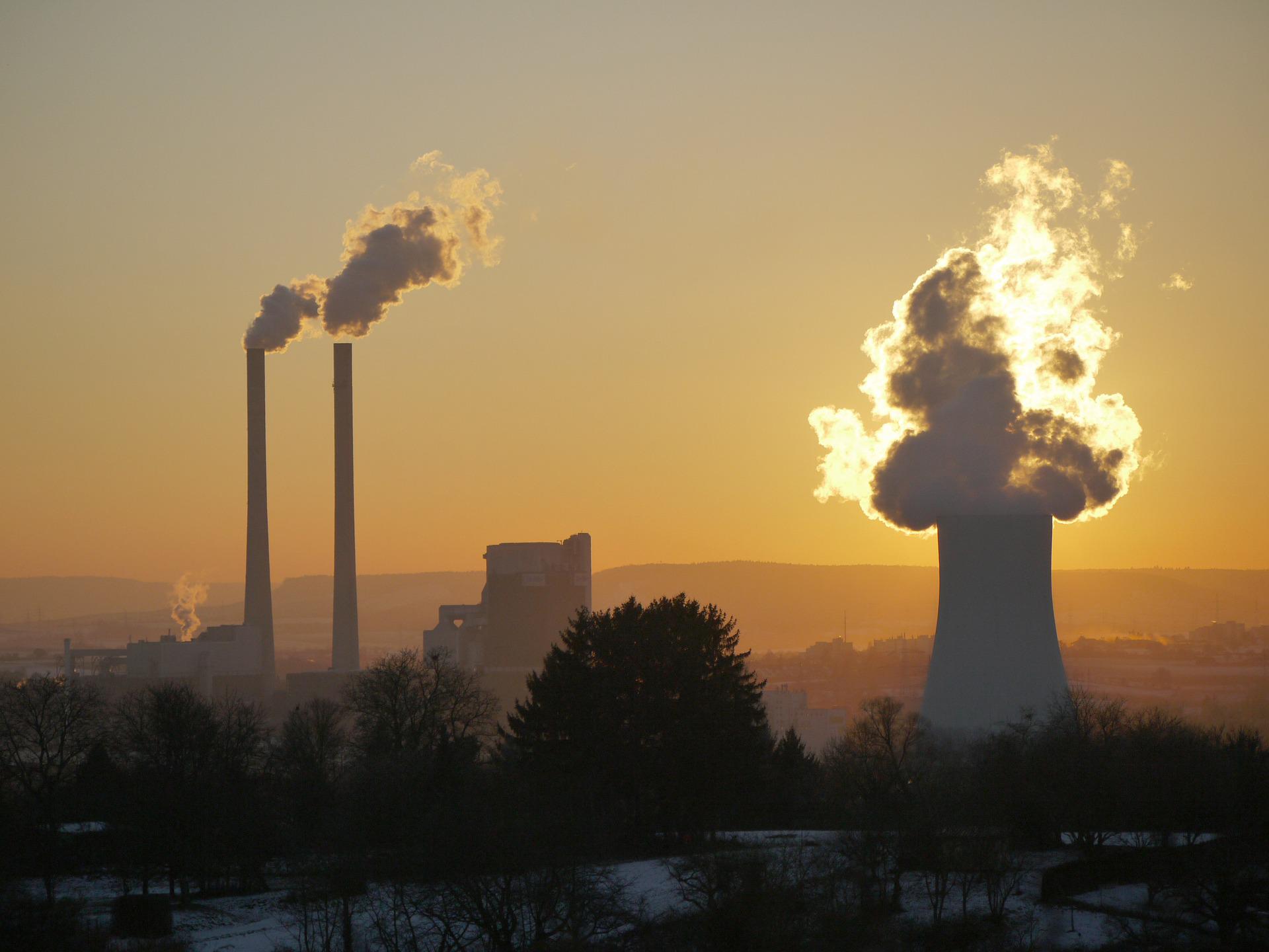 A power plant industry with two thin, long chimneys and a big chimney emitting smoke