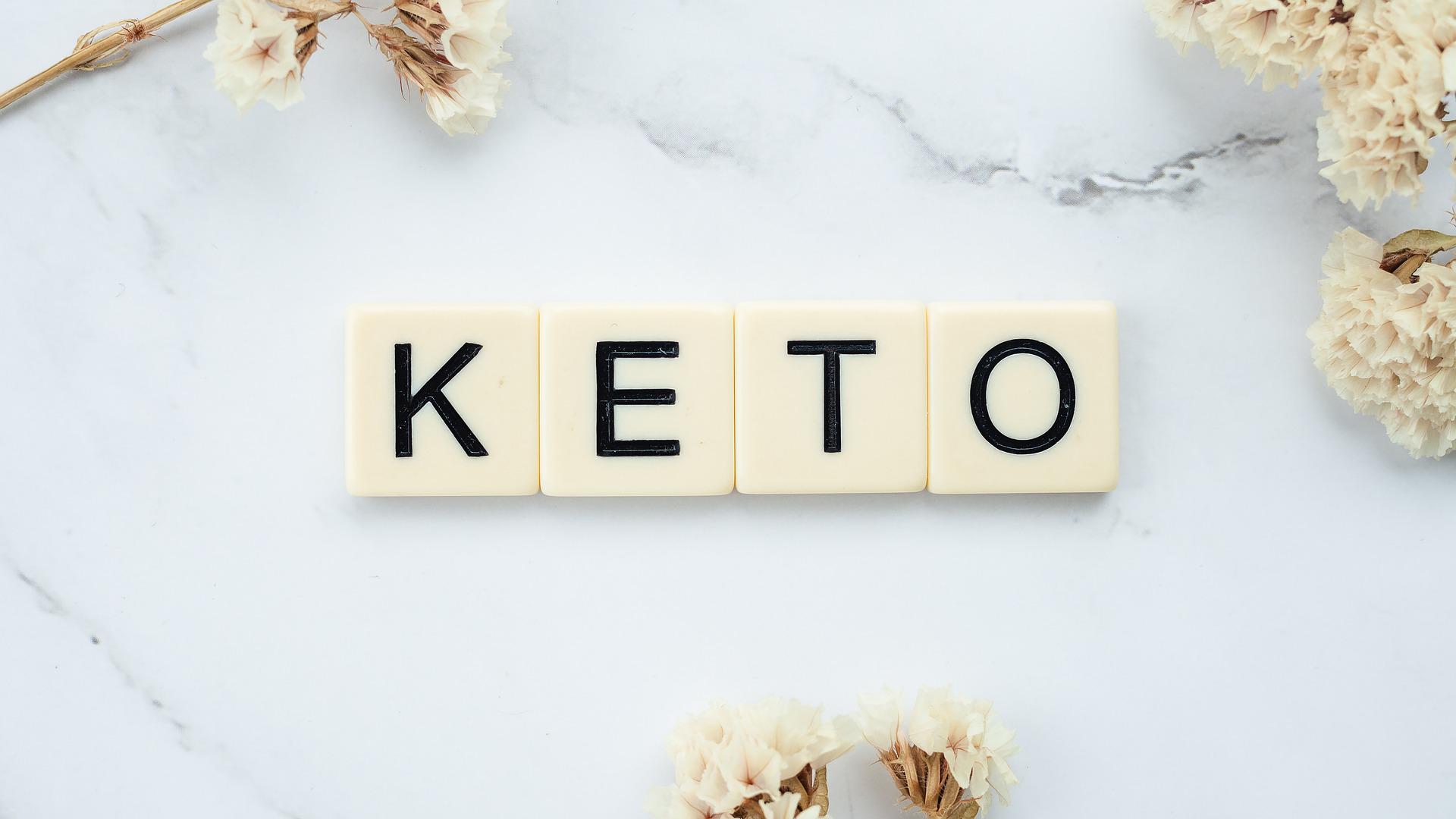 The word Keto spelled on some scrabble tiles sitting on a white surface