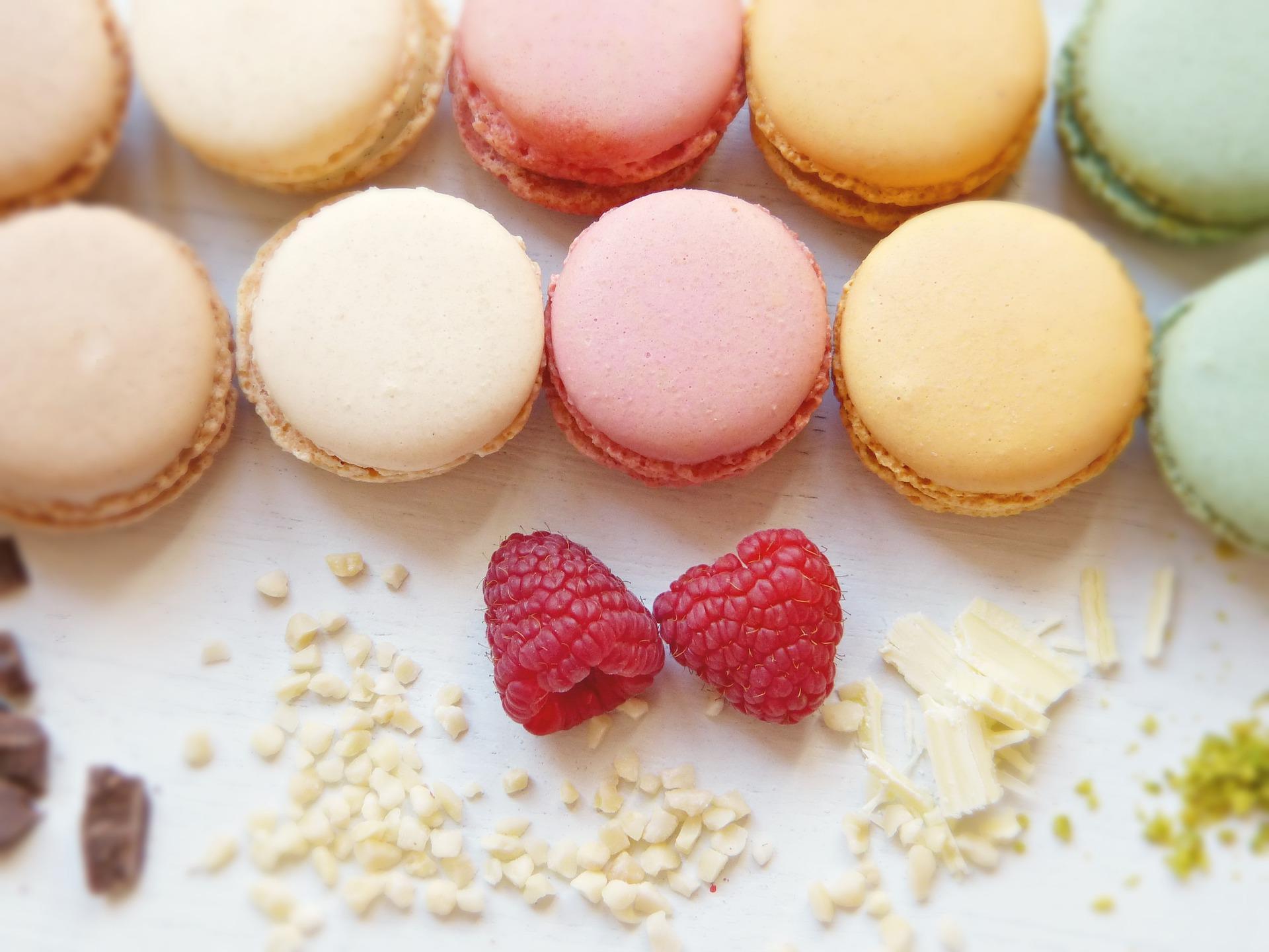 Ten pieces of macaroons with five different colors sitting beside two cherries